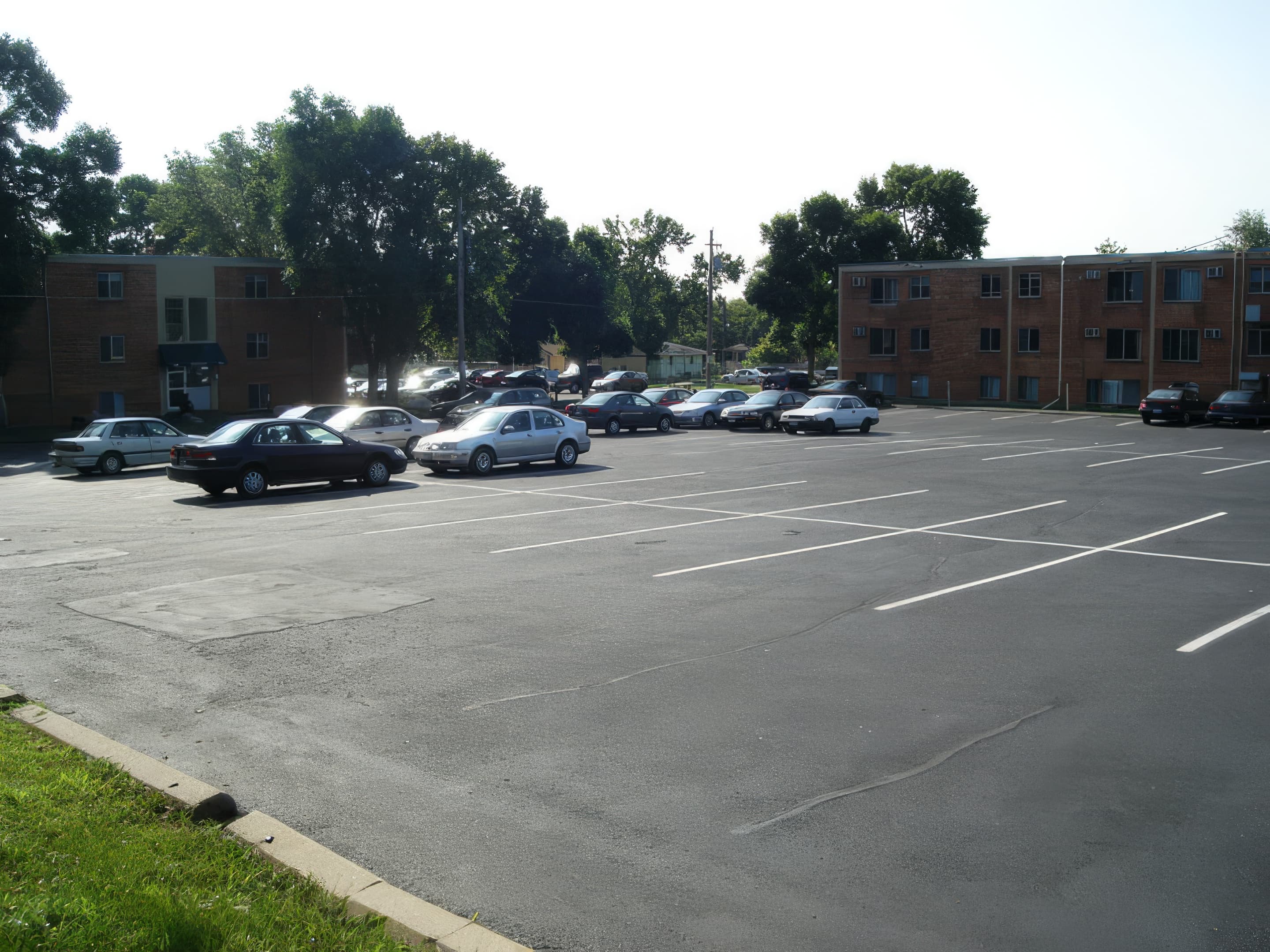 Arco Apartments complex view with parking and mature trees